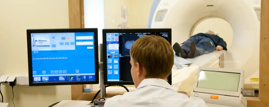 Illustrative imaging professional monitoring a patient from a scanning console