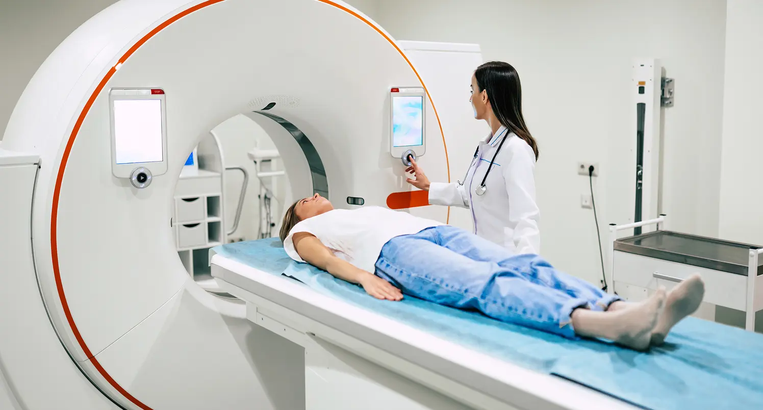 Illustrative patient lying on a CT scanner table with a clinician beside the gantry